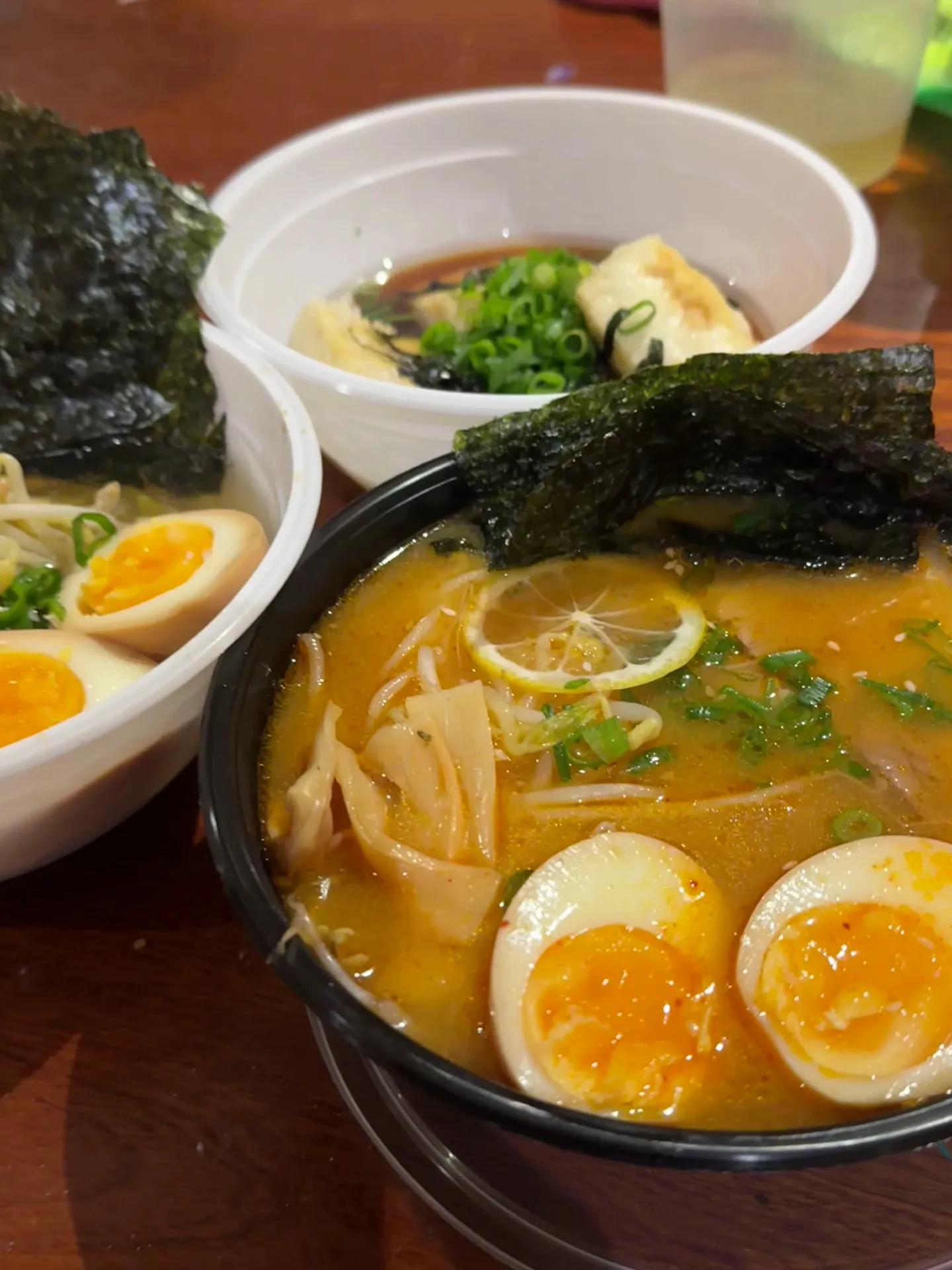 Spicy miso ramen in black bowl with orange broth and multiple side dishes