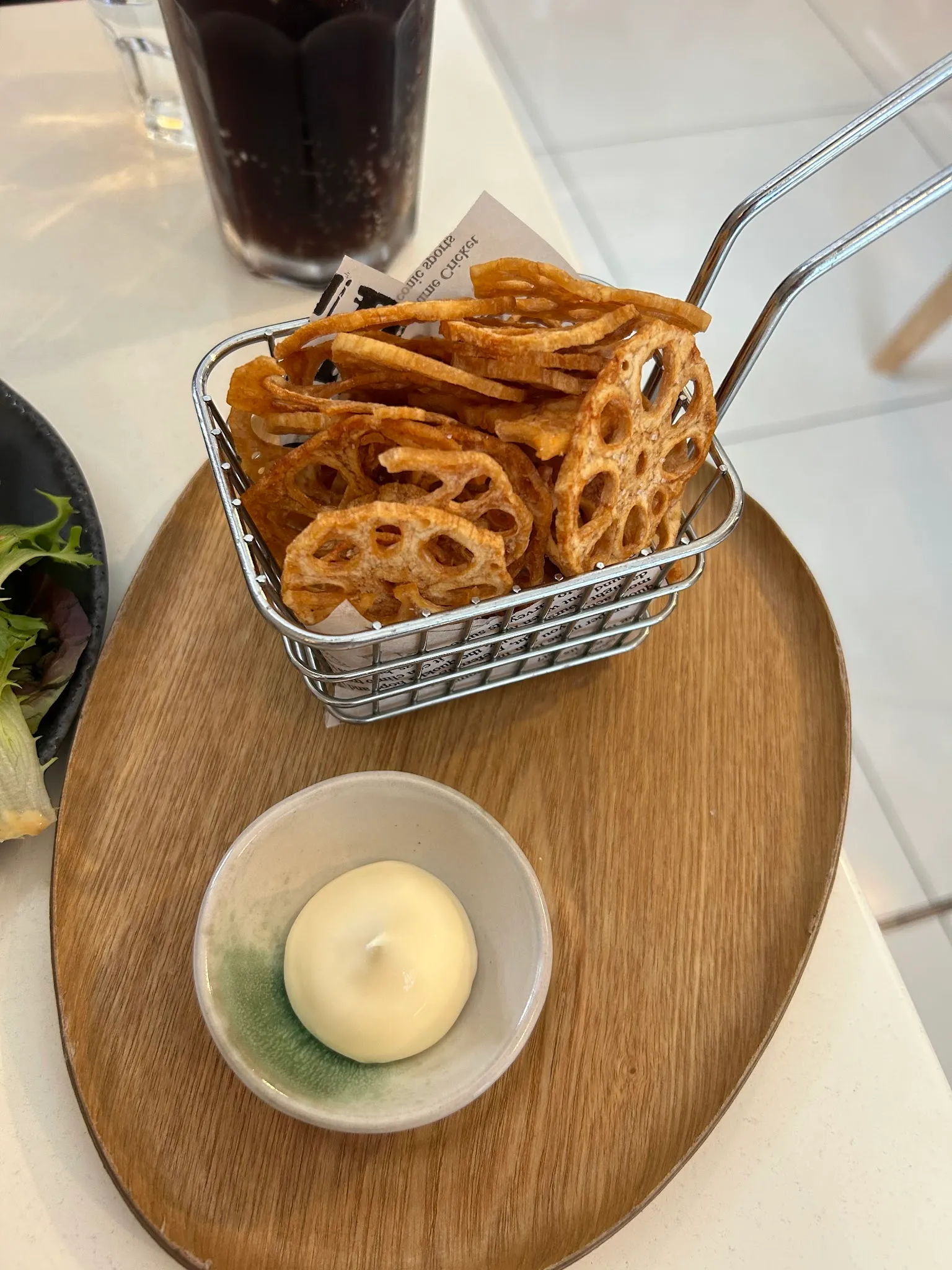 Renkon lotus root chips in wire basket with dipping sauce on timber board